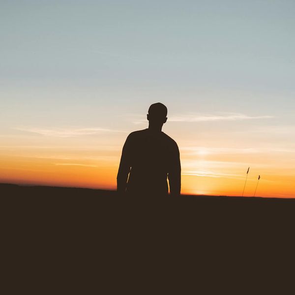 Silhouette of a person meditating against a calm, serene backdrop.
